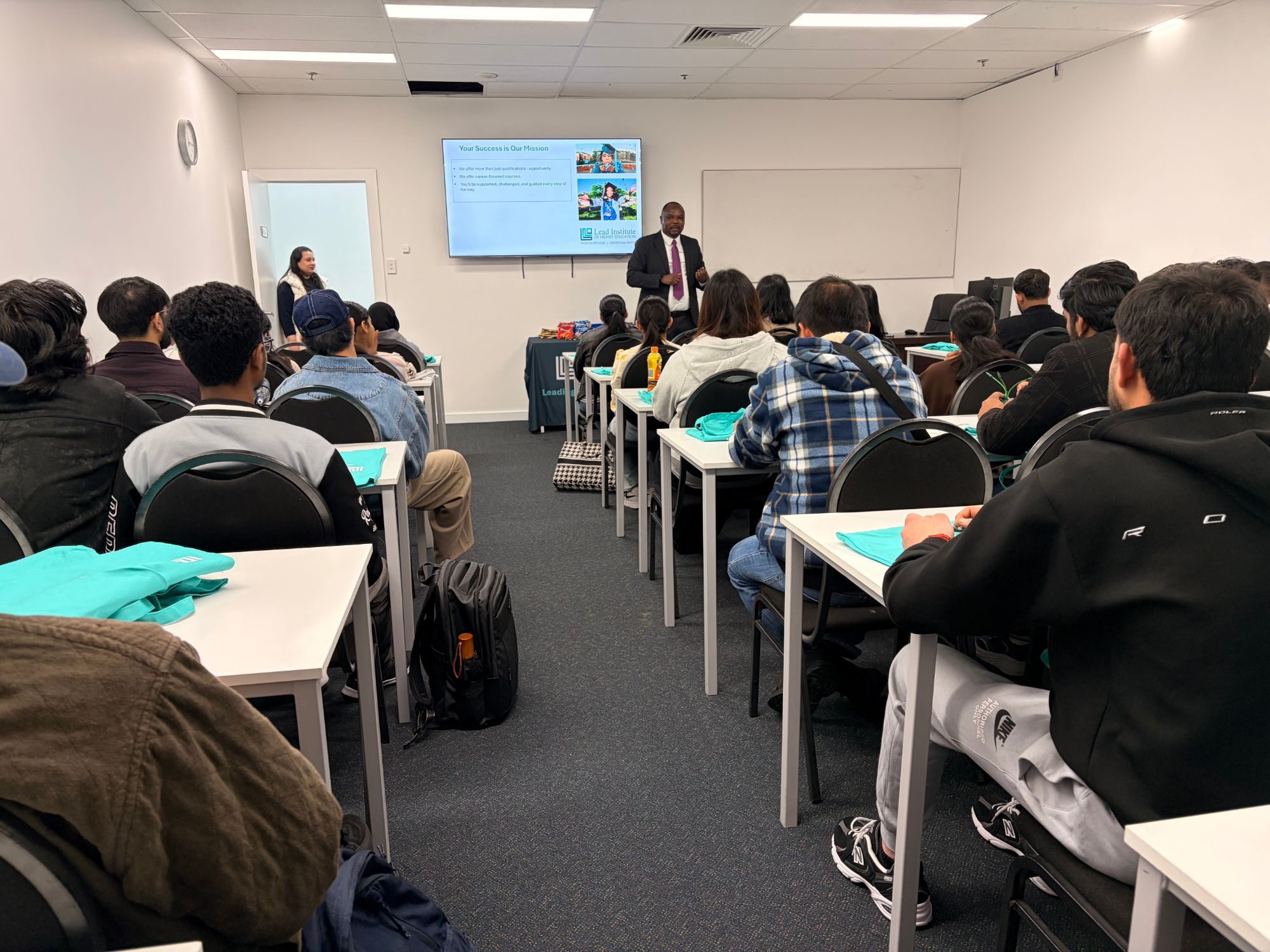 The classroom from the back: students in rows facing a presentation on the screen