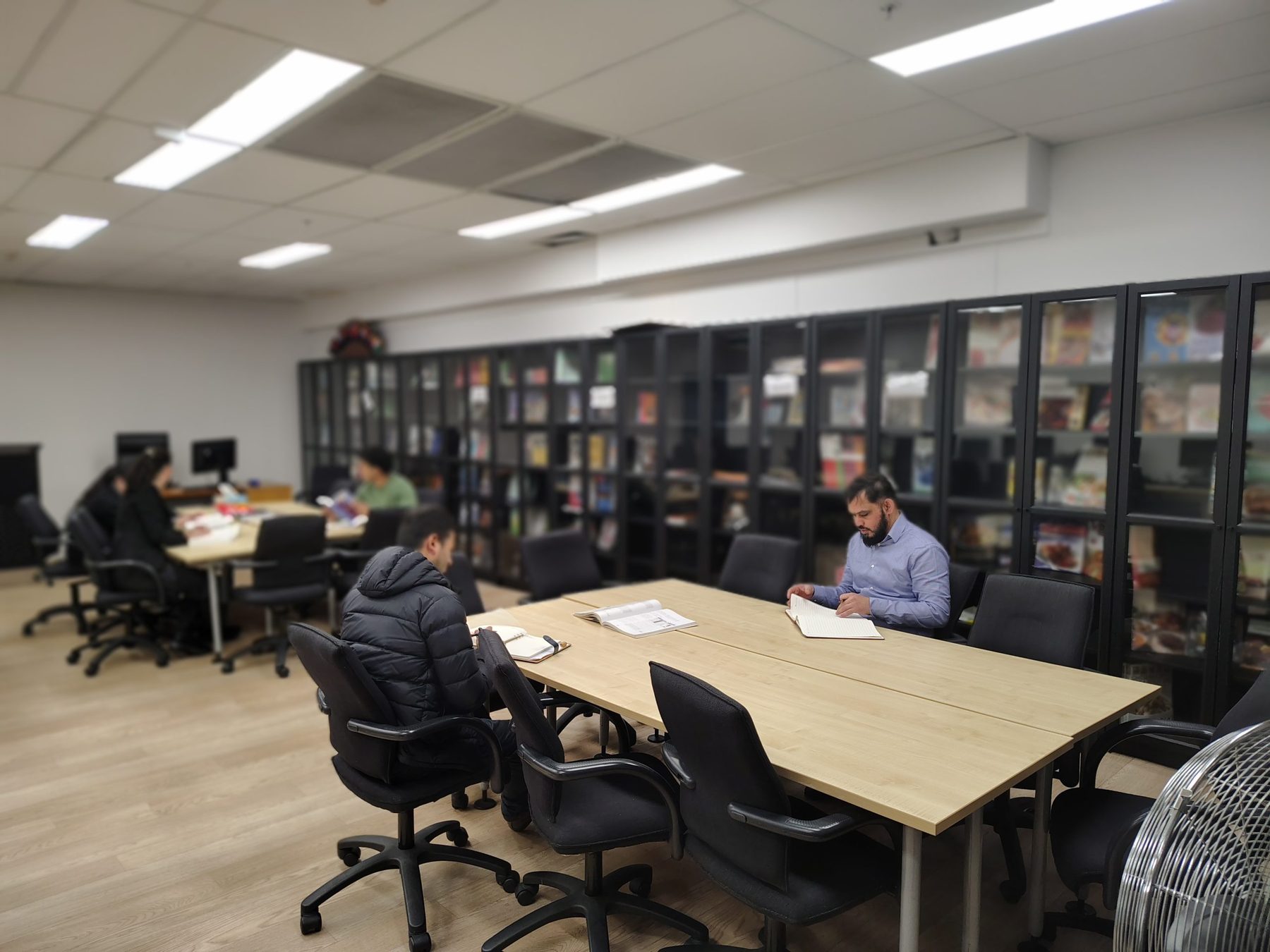 Students working at tables in the LIHE library, surrounded by bookshelves