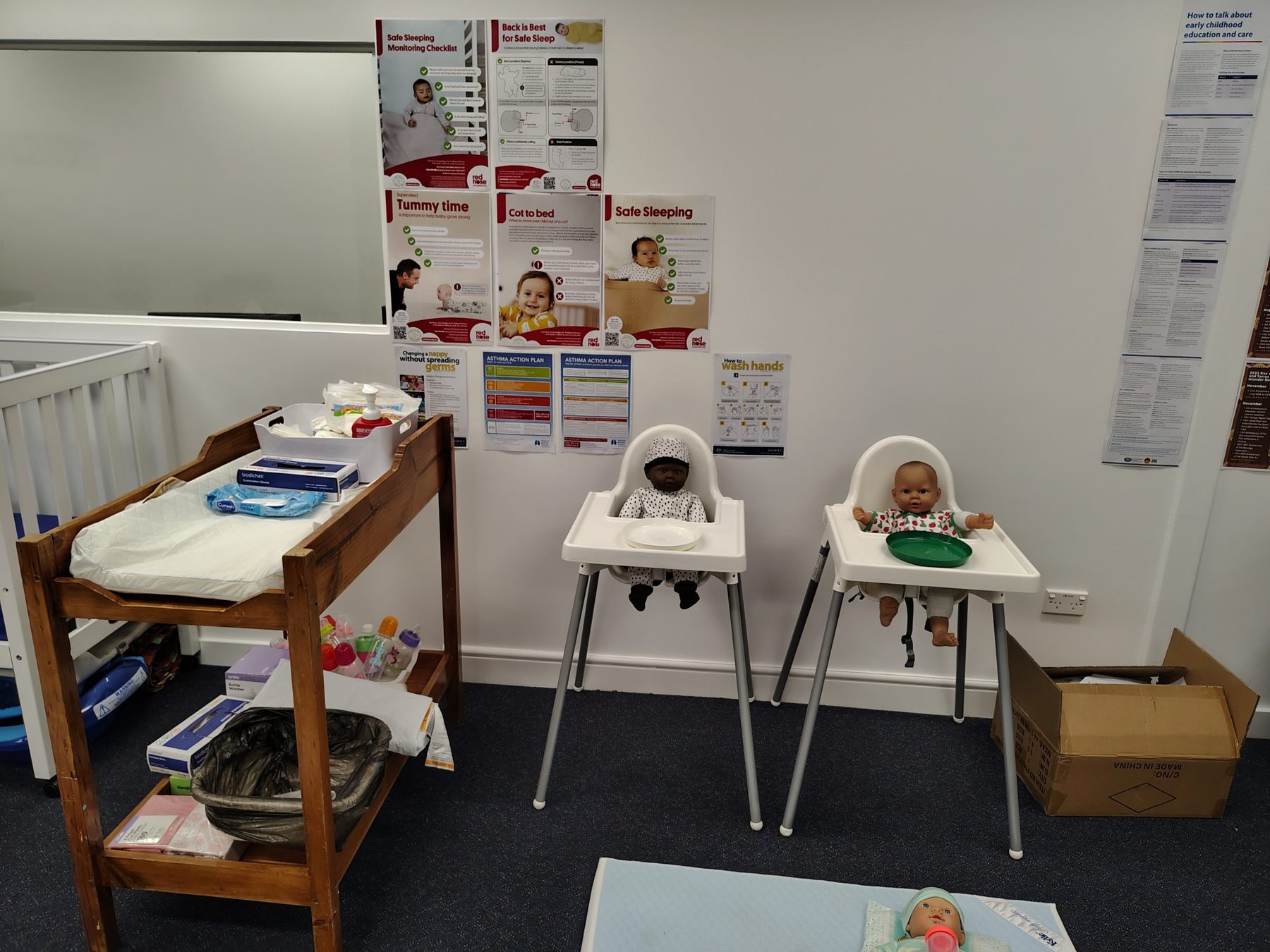 Infant care area of the simulation room, with a changing station, high chairs and safe-sleep posters